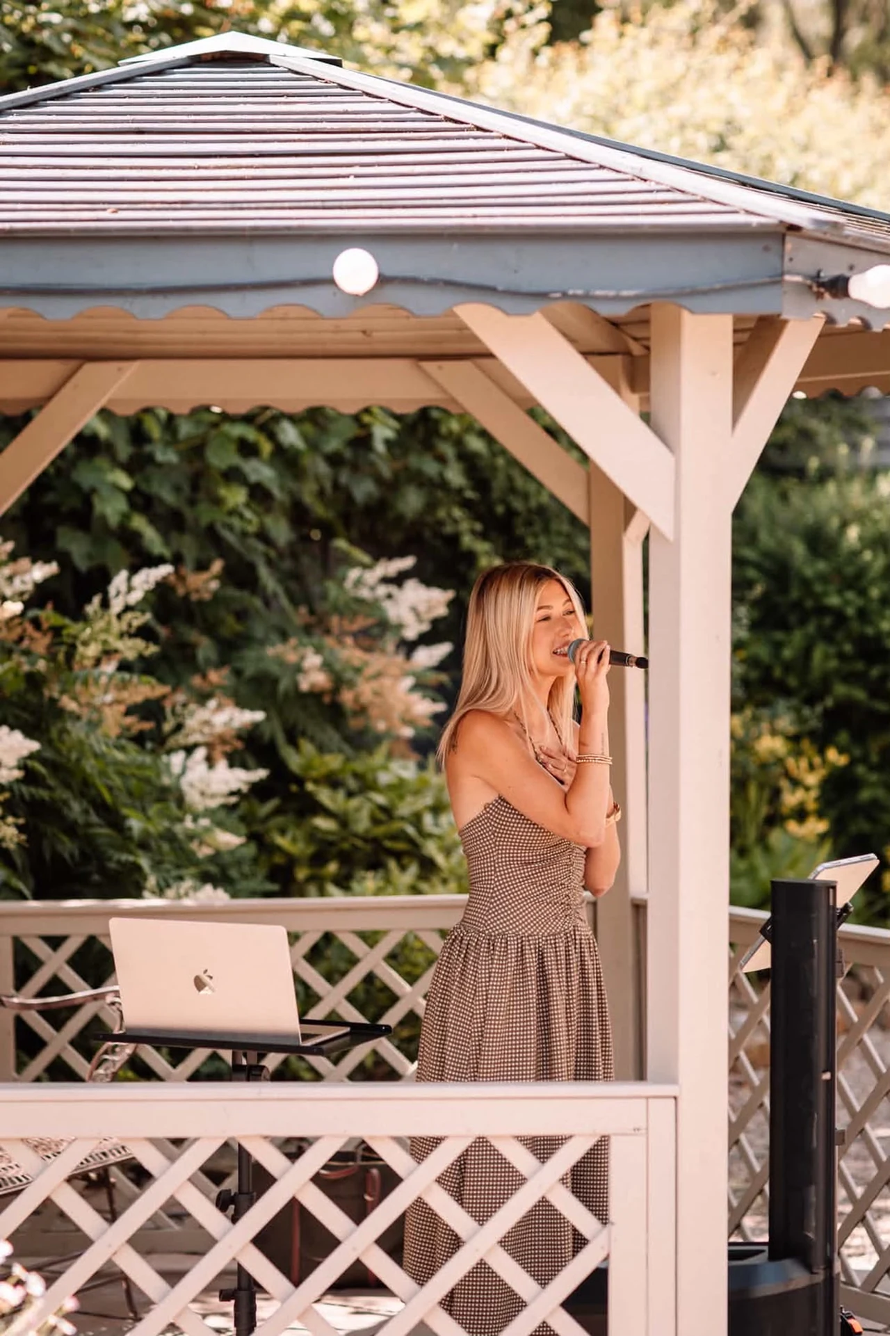 Caitie performing live beneath a gazebo at an outdoor wedding