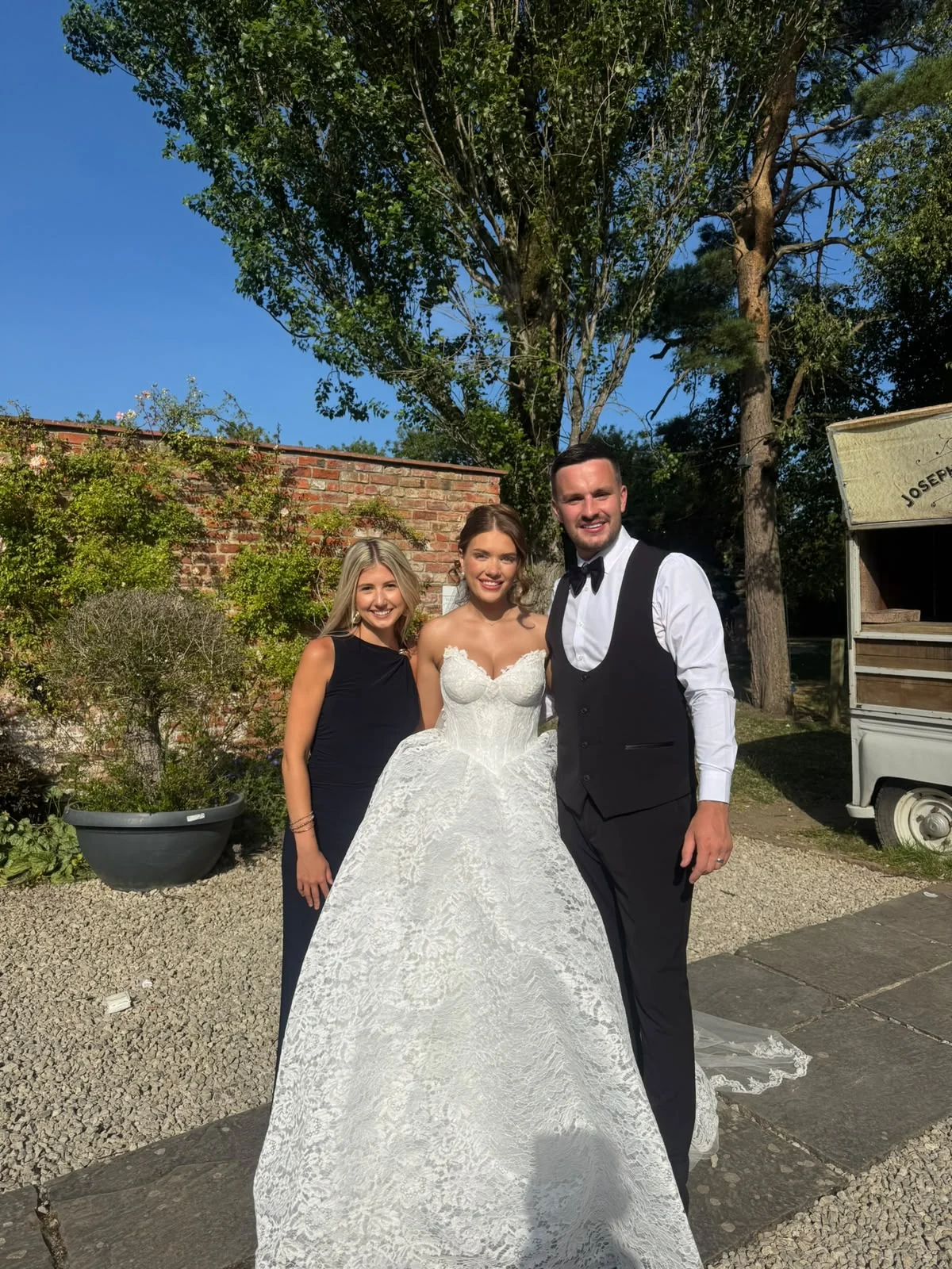 Caitie with a bride and groom at an outdoor wedding