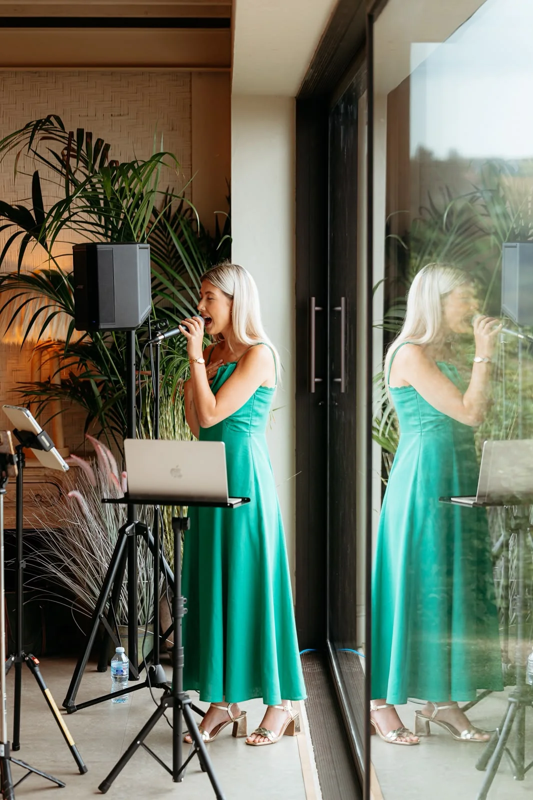 Caitie singing in a green dress beside a window